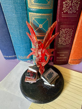 Load image into Gallery viewer, Decorative red fairy figure on a black base with books in the background
