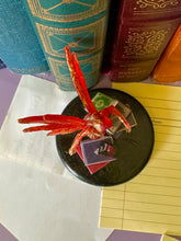 Load image into Gallery viewer, Small figurine on a black base with books and a notebook in the background

