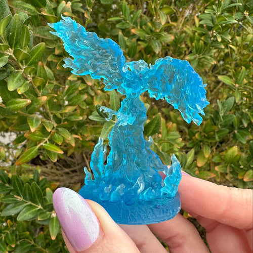 Blue phoenix with wings outstretched and fire extending to wrap around her talon feet 